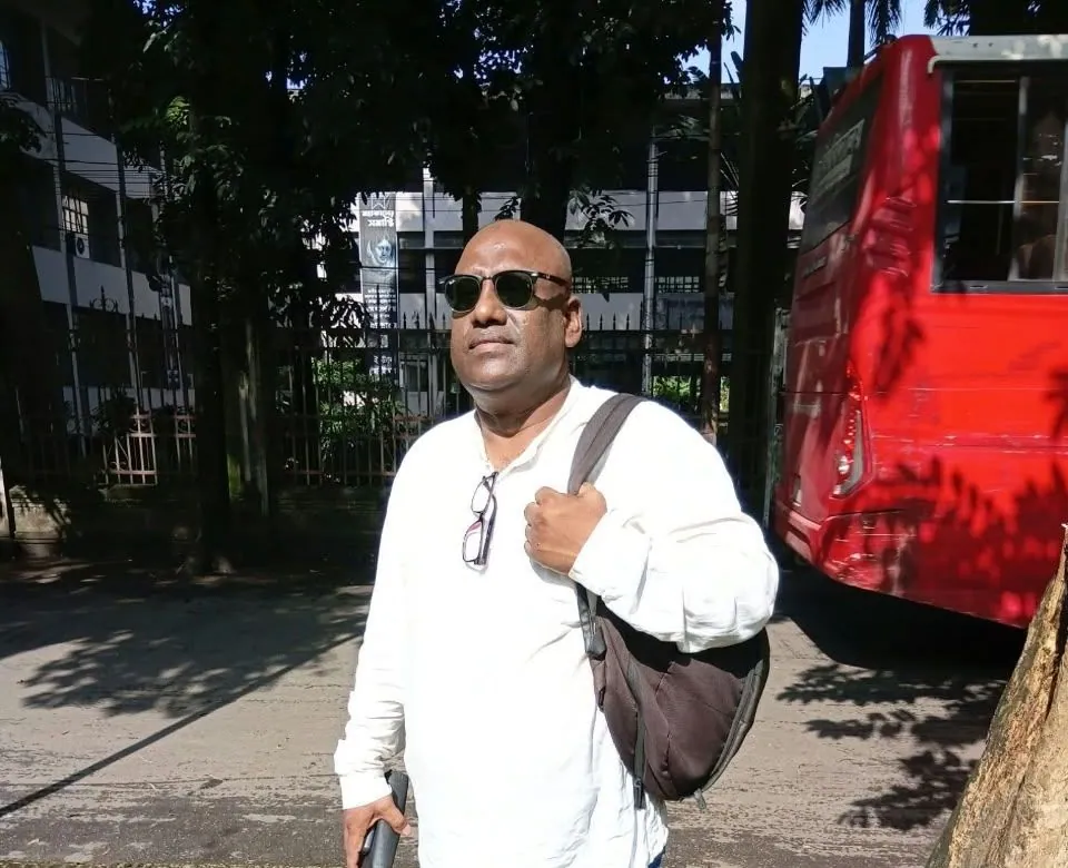 The Chairman in a white shirt, sunglasses and shoulder bag on a sunny road