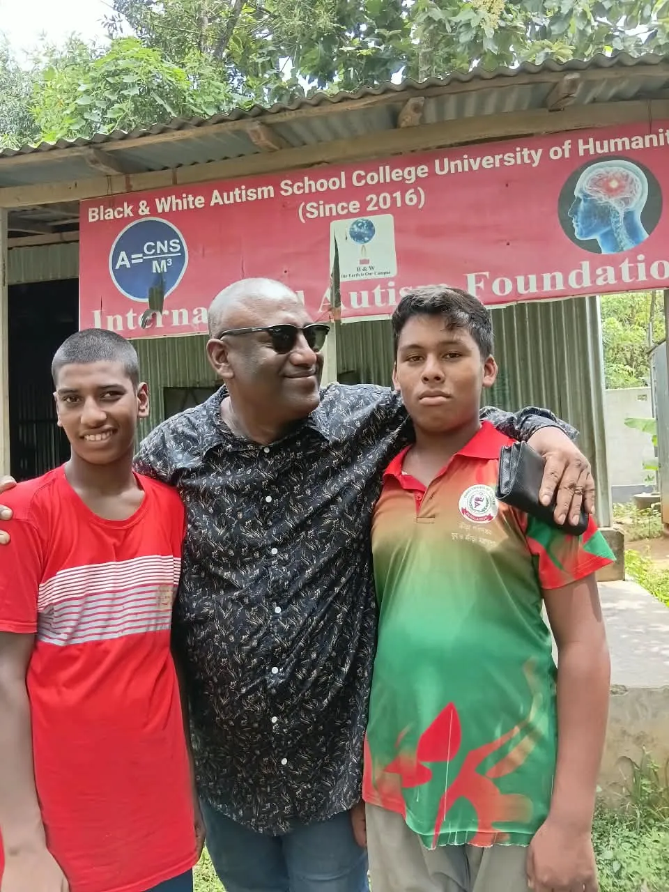 The Chairman with two boys in front of the school banner