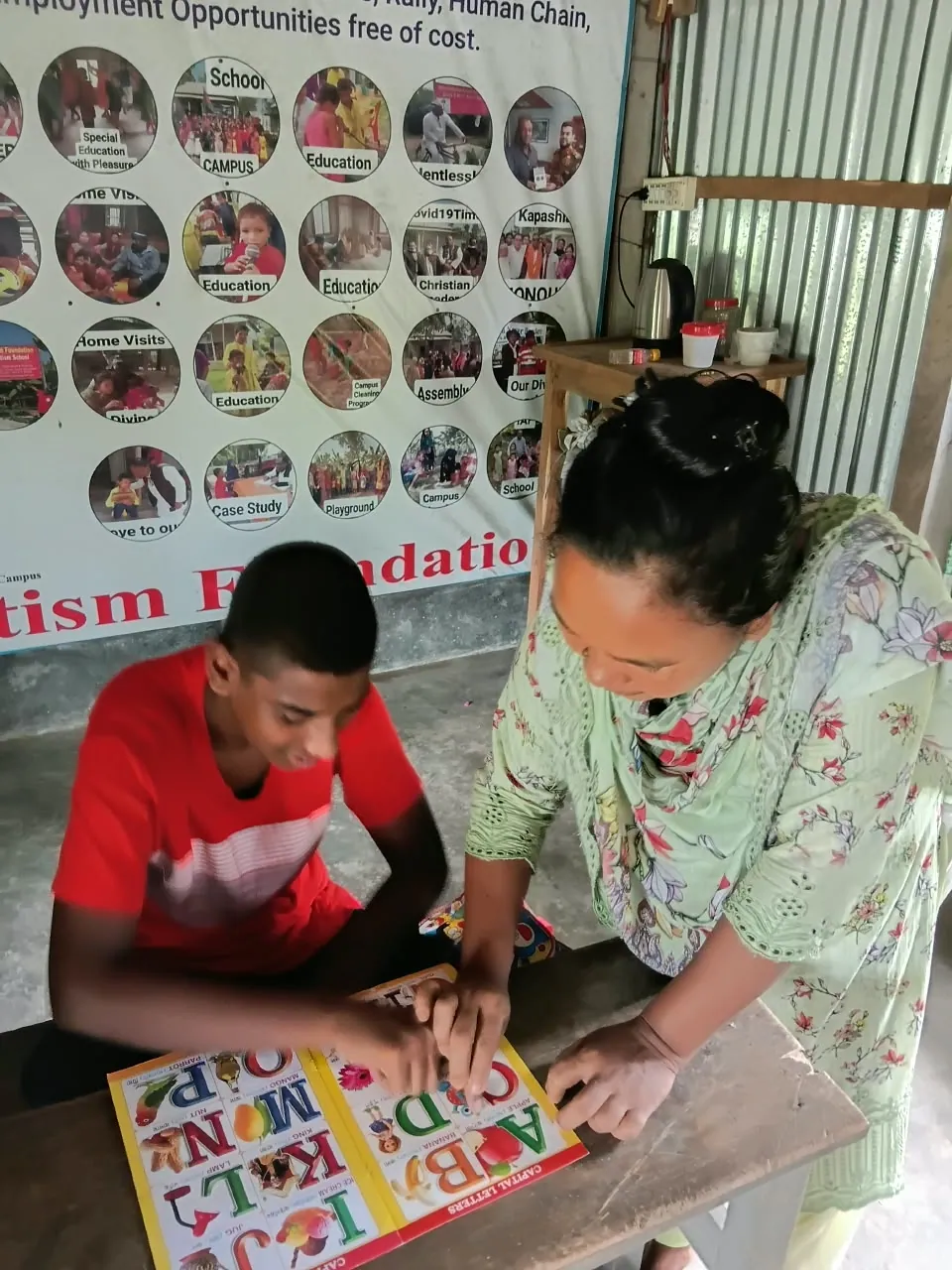 A teacher helping a boy trace letters in an alphabet book
