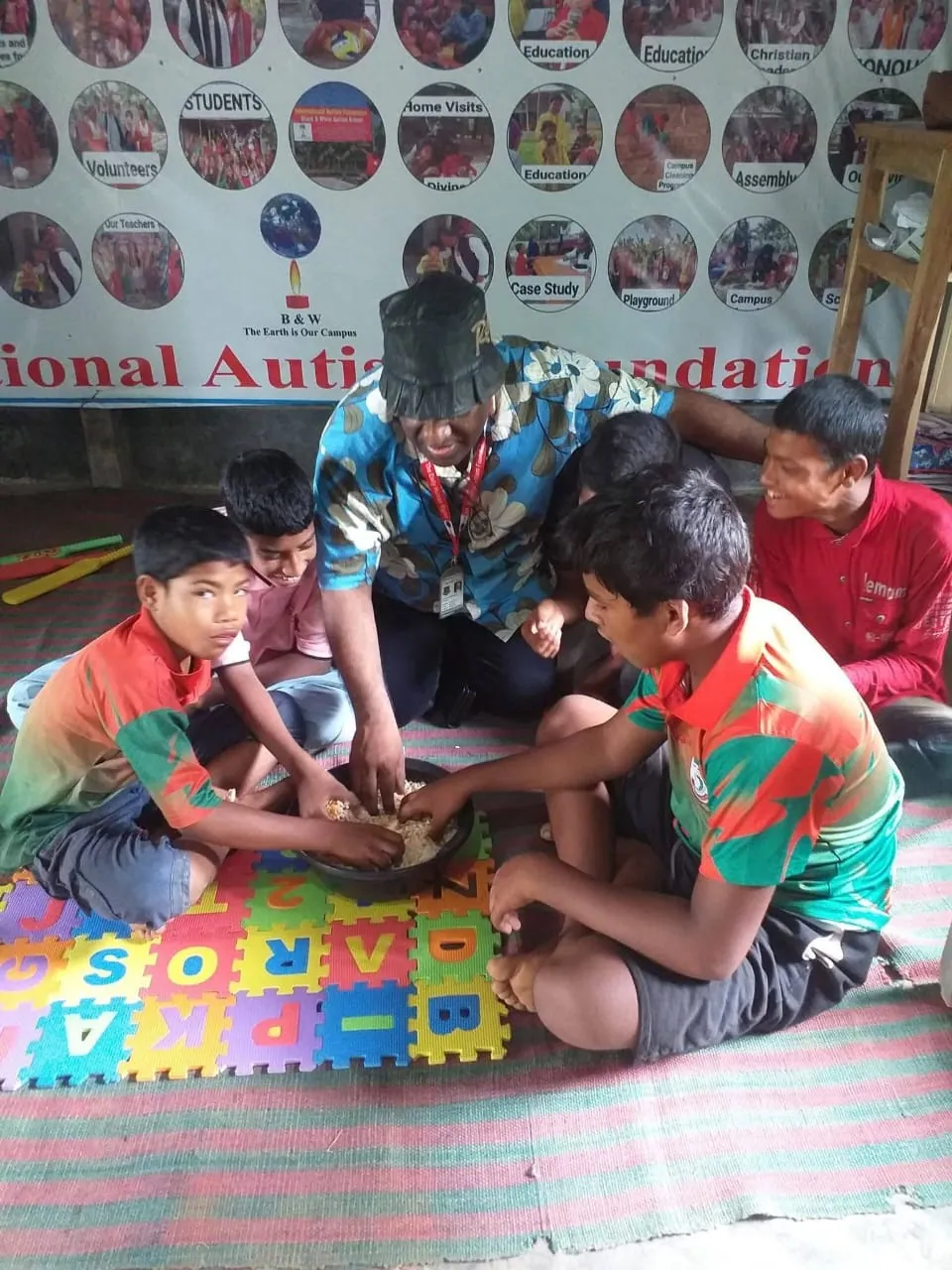 Boys and a teacher gathered around a colourful alphabet floor mat