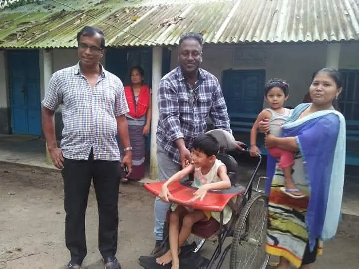 A family with a child in a wheelchair outside a village home
