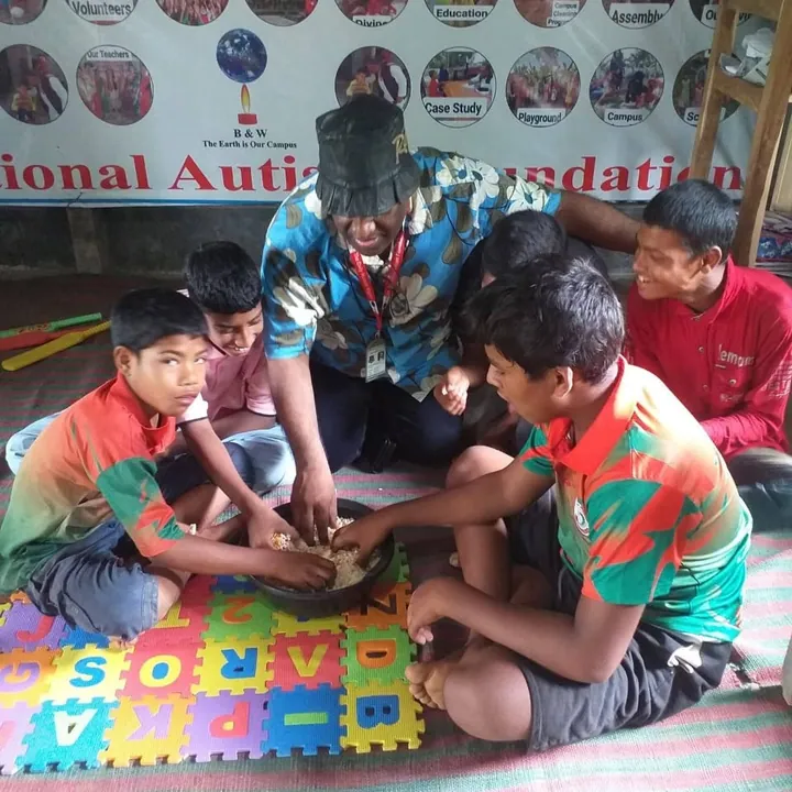 Boys and a teacher around an alphabet floor mat
