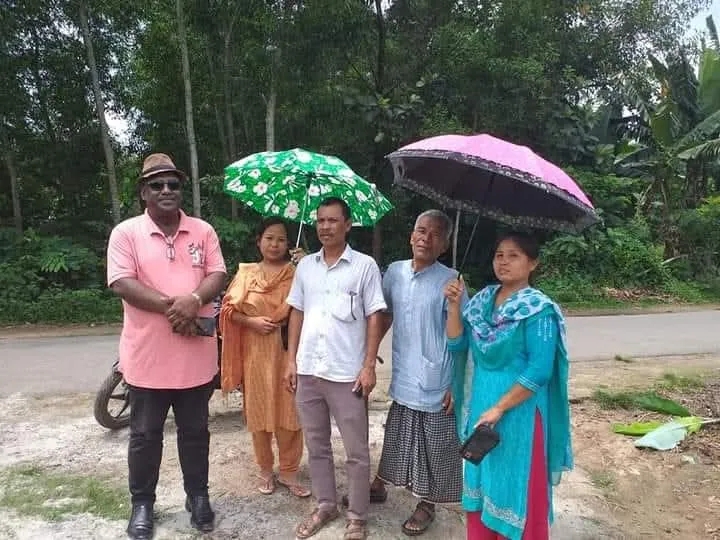 The Chairman with villagers holding umbrellas in the rain